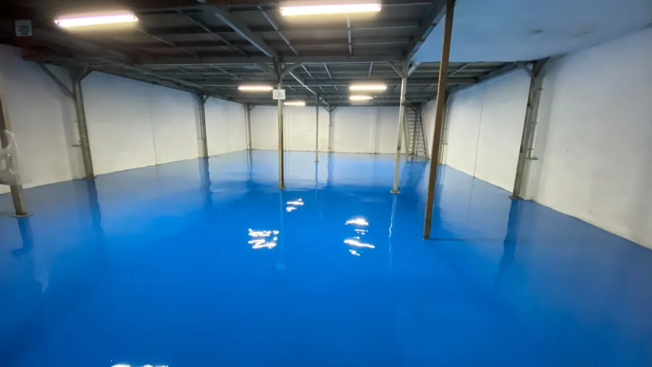 Lantai epoxy biru glossy di gedung produksi yang masih kosong